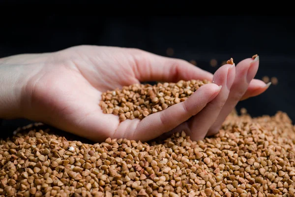 Bir elden çıkan karabuğday, yere düşen karabuğday lapası, arka planda bir dişinin elinde çiğ.