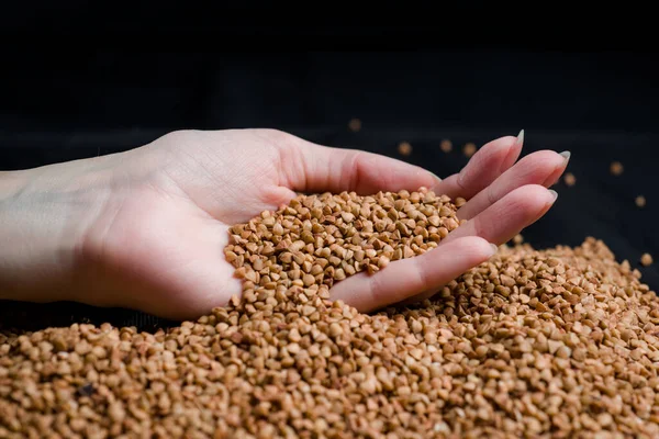 Bir elden çıkan karabuğday, yere düşen karabuğday lapası, arka planda bir dişinin elinde çiğ.