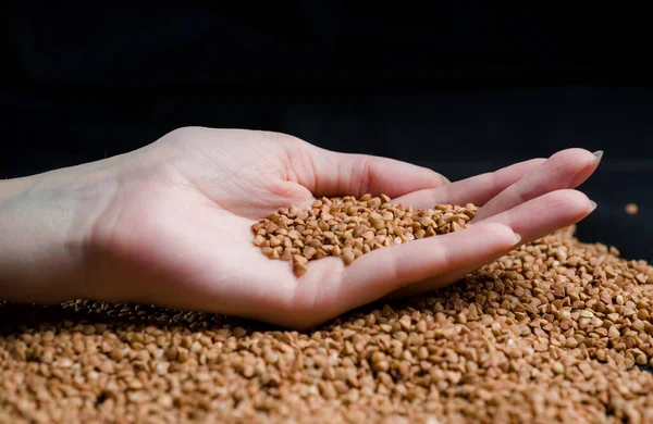 Bir elden çıkan karabuğday, yere düşen karabuğday lapası, arka planda bir dişinin elinde çiğ.