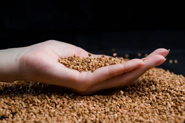 Bir elden çıkan karabuğday, yere düşen karabuğday lapası, arka planda bir dişinin elinde çiğ.