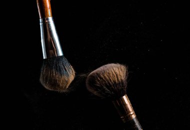 Uzay tozu gibi koyu bir arkaplanda farklı renklerde makyaj fırçası