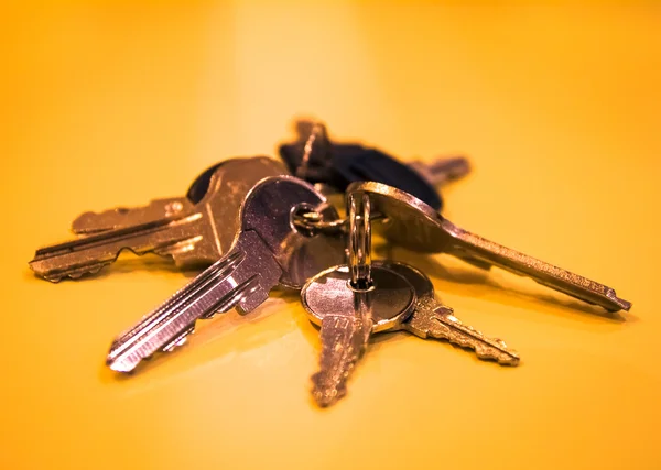 Bunch of keys on golden-yellow table — Stock Photo, Image