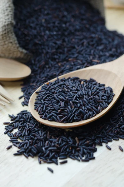 Rice berry in a wooden ladle, on wood table. — Stock Photo, Image