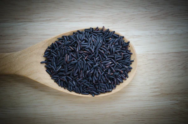 Rice berry in a wooden ladle, on wood table. — Stock Photo, Image