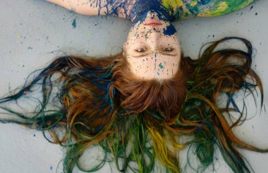 Esmer, kızıl saçlı, uzun saçlı, mavi ve yeşil renkli bir kadının alışılmadık etkileyici portresi. Dekoratif, yaratıcı, soyut vücut boyama, makyaj, uzay fotokopisi.