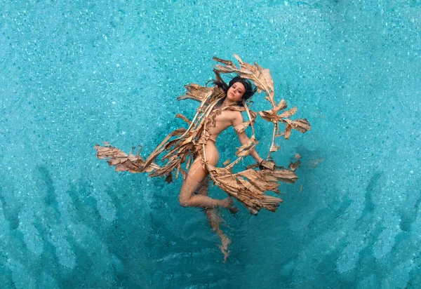 一个年轻貌美的性感女子 美人鱼 飘逸优雅地在干枯的香蕉树叶上悠闲自在 碧蓝的湖水 复制着空间 — 图库照片
