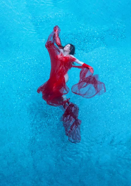 美しいセクシーな若い女性は スイミングプールのターコイズブルーの水に包まれた赤い布に人魚のように浮かぶ エレガントなエロティックな夢 ウォーターバレエ コピースペース — ストック写真