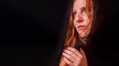 Baştan çıkarıcı, genç, seksi bir kızıl saçlının yakın plan portresi, uzun kıvırcık saçlı, siyah saçlı, kıvırcık elleri ve katlanmış elleri olan güzel bir kızıl kadın,