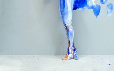 Güzel bacaklara ve ayaklara panoramik bir manzara. Sanatsal açıdan soyut, mavi ve beyaz boyalı bir balerin. Yaratıcı vücut resimleri, kopyalama alanı.