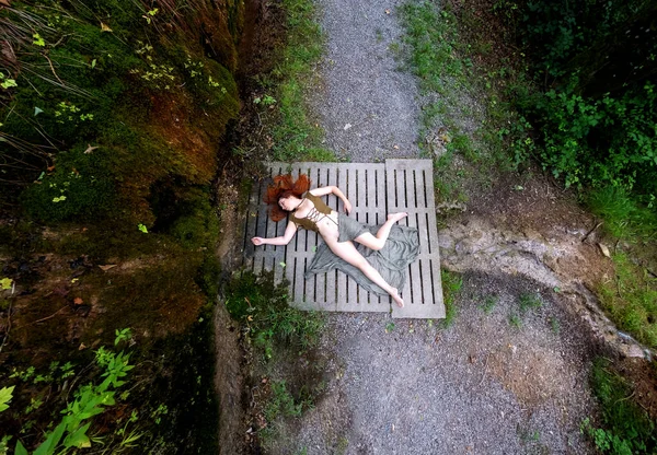 一个性感的 年轻的 红头发的女人的头像死在青苔丛生的斜坡上的一座混凝土桥上 怎么了 复制空间 — 图库照片