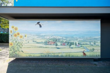 Sanatsal olarak boyanmış mavi evin bir parçası, kırsal duvar resmi, ayçiçekleri ve hayvanların eski bir vitrinde leylek ve tavşan olarak resmedilmesi, duvar resmi, Wuppertal Oberbarmen, Berlinerstrasse