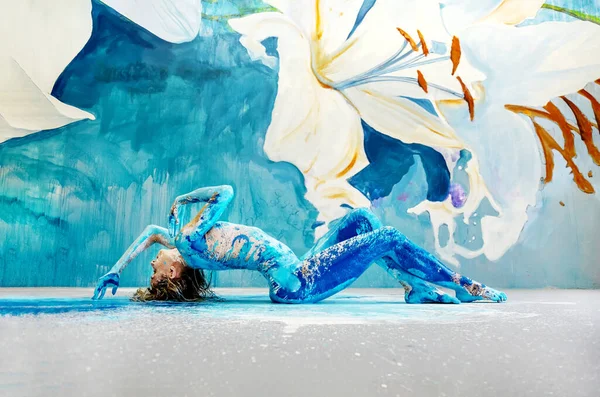 年轻性感的金发女子 蓝绿色和白色的画像 躺在地板上跳芭蕾舞 全身赤身裸体 在艺术家工作室的白百合墙前 复制空间 — 图库照片