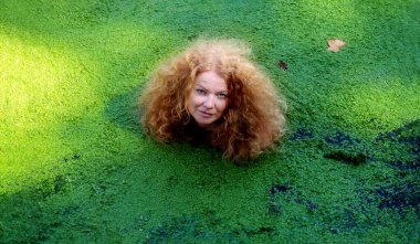 Rüya gibi güzel, büyülü, olgun, baştan çıkarıcı peri masalı denizkızı portresi. Nehirde kızıl saçlı, yeşil ördek otlu, kopya uzay.