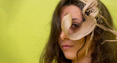 Baştan çıkarıcı, güzel, genç, seksi esmer bir kadının portresi. Bakış açısı, vizyonu, görüşü, yuvarlanmış kuru muz yaprağının içinden bakıyor. Bir gözetleme deliği gibi.