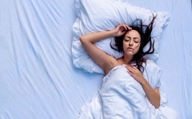 Çekici, esmer, seksi kadın portresi, çarşafların üzerinde vahşi saçlar, yatakta dinlenme, Pazar sabahı, taze yumuşak çarşaflar ve yataklar, fotokopi alanı.