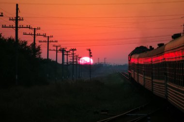 Karşı günbatımı, demiryolu gün batımında yolcu treni rides
