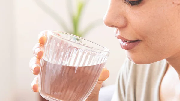 Genç bayan bir bardak su içiyor.