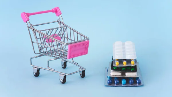 Tablets pills and shop trolley on a blue background