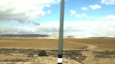 Sıcak Negev yol ve yerleşim yerlerini terk ediyor kumların arasında ve mavi gökyüzünün altında beyaz bulutlu seyrek bir bitki örtüsü