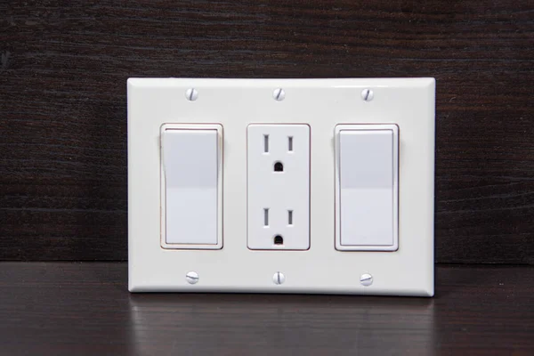 İki anahtar ve ortada bir soket üç katlı beyaz kaplama ile kaplıdır.