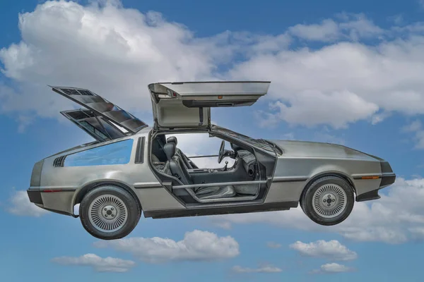 DeLorean DMC-12 kapılı araba, beyaz bulutlu mavi gökyüzü prototipi.
