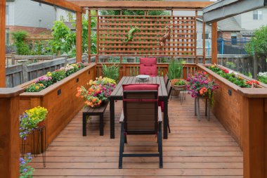 Masası, sandalyeleri ve iki tane de ahşap çiçek yatağı olan güzel bir güverte.