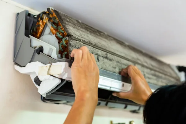 Selective focus to air conditioner filter that a lot of dust with blurry hand of male technician. Basic cleaning dust in air conditioner at home with yourself.