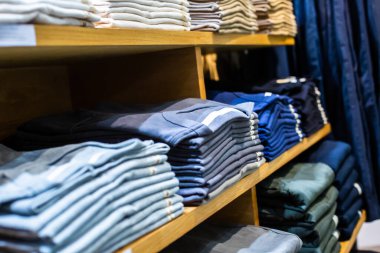 Dükkanda katlanmış birçok kıyafete seçici odaklanma. Bir sürü kıyafet. Satın alıp satma kavramı, beyefendi ve sıradan moda gömleği..