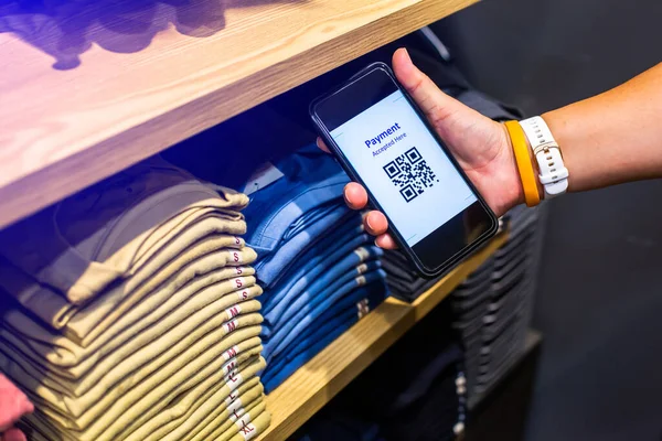 Customer hand using smart phone to scan QR code tag with many row of clothes  to accepted generate digital pay without money. Qr code payment concept.