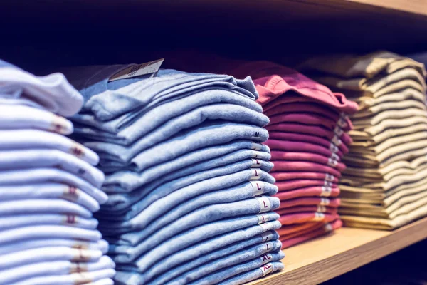 Selective focus to many clothes folded in the shop. Many stack of clothes. Concept of buy and sell, gentleman and casual fashion shirt.