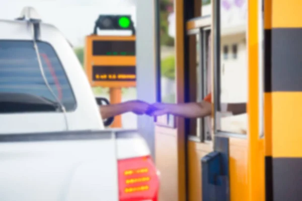 Blurry image of hand of driver pay for the expressway. Driver pays money to a cashier for a toll road or toll gate motorway entrance. Hand paying express toll way on the road. Pay express way.