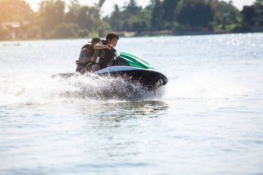 Antrenörüyle jet ski yapan Asyalı bir genç. Dalga koşucusunda kayak yapan genç bir çocuk. Genç adam tropikal denizde şahsi su aracında. Jetski eğitimi. Kumsal tatilinde spor ve okyanus aktiviteleri.