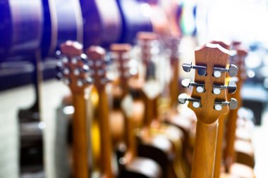 Selective focus to guitar tuning knob with blurry  many guitar in musical showroom at musical store. Instrument concept.