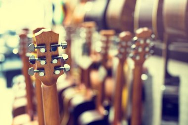 Gitar akort düğmesine seçici bir odak. Müzikal mağazasındaki müzikal galeride bulanık bir sürü gitar. Aygıt konsepti.