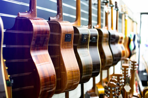 Classic guitar drapped in a row in a huge musical shop, instrument shop, guitars are hanging in musical showroom at musical store. Instrument concept.