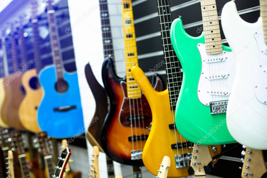 Selective focus to electric guitar with blurry guitars are hanging in musical showroom at musical instrument store