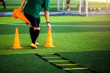 Koç, futbol antrenmanı için işaret külahlarını koşu ve atlama için koyuyor. Futbol Akademisi.