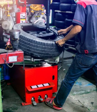 Atölyedeki dengeleyici üzerinde araba tekerleğini dengelemek için seçmeli odaklanma. Pnömatik ingiliz anahtarı olan tamirci tekerleği söker. Tamirci araba tekerleğini tamir ediyor. Erkek tamirci araba garajında tekerleği tamir ediyor.