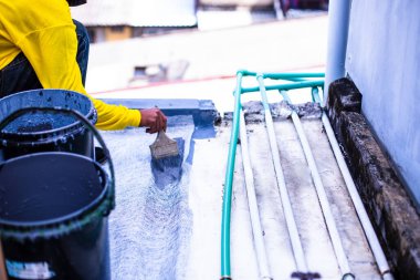 Boyacı, su geçirmez, ağları güçlendiren, su geçirmez güverte döşemesini tamir eden fiber cam üzerindeki gri zemini boyuyor..
