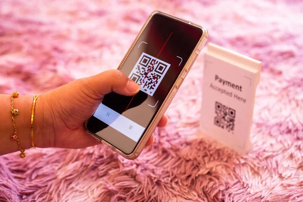 Hand holding smart phone to scan QR code payment on white background. The concept of cashless technology or digital payment.