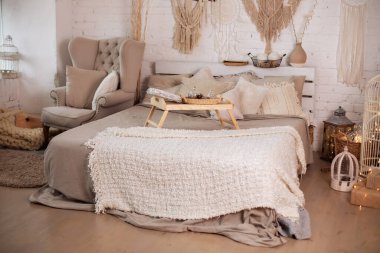 Yatakta ahşap kahvaltı tepsisi. Noel süslemeleri yatak odası İskandinav iç dekorasyonu koltuğu ve rahat yatağı yatak ve yastıkların üzerinde küçük bir masa, kopyalama alanı. konsept yeni yıl ve tatiller.