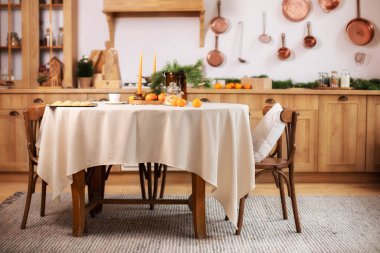 Vazodaki köknar dalında, Xmas kurabiyeleri. Sıcak ahşap mutfak dekore edilmiş Noel ya da yeni yıl. Yuvarlak masa ve sandalyeli İskandinav mutfağı. Kırsal tarzda şık bir yemek odası.. 