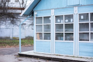 Kış günü terası olan ahşap, parlak, mavi bir ev. Gri çatılı, harici bir kır evi. Büyük cam pencereli ve ahşap verandalı iç ev.. 