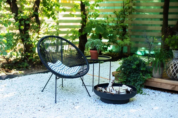 房子的阳台 有黑色的阿卡普尔科扶手椅 咖啡桌和盆栽的绿色植物 后院里花园的金属黑色壁炉碗 屋外的庭院里的家具 放在前花园的卵石上 — 图库照片