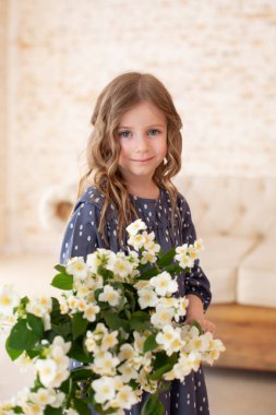 Anneye bir buket çiçekli mutlu çocuk. Anneler Günü. Bir buket yasemin çiçeğiyle gülümseyen kıvırcık kız. Çocukluk. Kutlama. Doğum günü için çiçekli kız. Paskalya. Bahar çiçekleri  