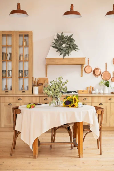 Stylish dining room with furniture in retro style. Cozy Wooden cuisine  decorated with summer decor.  Kitchen utensils, dishes, plates. Interior design scandinavian kitchen with round table and chairs