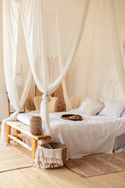 Beyaz yatak odası, kahve masası, saman lambası ve yastıklı rahat yatak, fotokopi odası. Akan beyaz perdeli bir yatak. Sıcak İskandinav dekorasyon odası. hygge dekoru evde