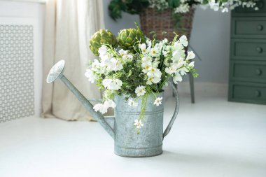 Vintage rustic garden Tool at home. Summer bouquet of flowers in watering can. Bunch of daisies in watering can. Gardening concept. Daisies and plants in zinc metal vase