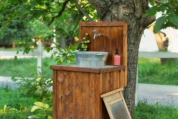 Handmade wooden Wash basin with soap in garden for hands cleaning in summer. Hand outdoor washing facilities to prevent the spread of virus or disease. Vintage outdoor sink for rustic decor in yard