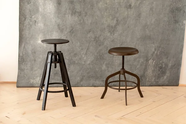 black minimalist metal chairs against grey background. Concept modern interior and design furniture in room. High stool in loft style. Retro Bar chair. Vintage wooden metal chair. Tall standing table.